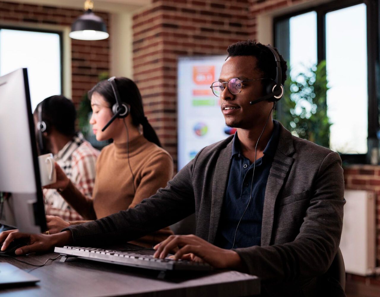african-american-helpline-employee-working-call-center-reception-with-multiple-monitors-male-operator-using-telecommunication-help-clients-customer-service-support-remote-network
